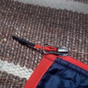 Detail táhla a jezdce hlavního zipu bundy Hannah Maxton.