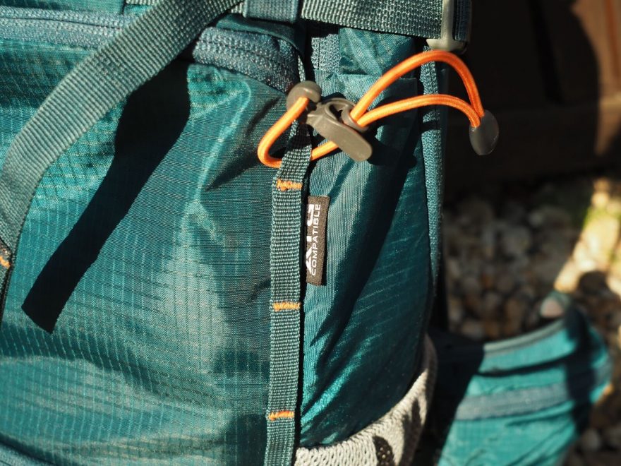 Řetízky na čele batohu slouží pro uchycení síťky na helmu ale i dalších předmětů. Gumičky kompatibilní s trekovými hůlkami ATG pak podtrhují univerzálnost batohu.