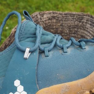 Detail na kovová očka a provlečení tkaničky, která po své délce mění svou tloušťku.