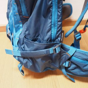 Spodní kompresní popruh má na sobě látkový rukávek. Na obou stranách batohu jsou i menší kapsičky.