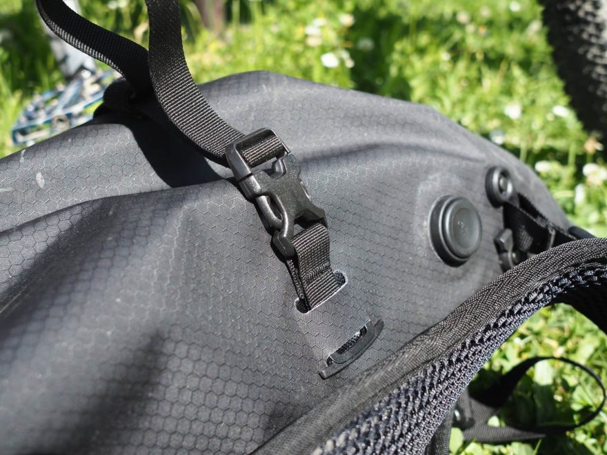 Kompresní popruhy batohu Atrack BP 25 lze jednoduše odejmout. Přichyceny jsou plastovými kotvičkami v průřezech. Horní popruhy mají plastové spony, takže je lze rozepnout