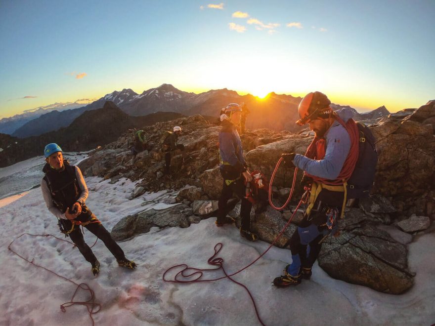 Slunce vychází zpoza temných čtyřtisícových obrů, Lagginhornu a Weissmiesu. Hohlaubgrat, Allalinhorn, Wallis, Alpy, Švýcarsko.