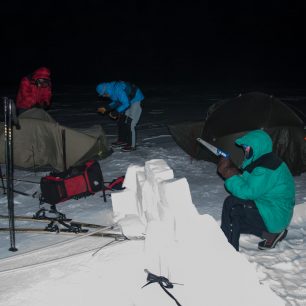 Stavba sněhové zástěny, která chrání stan proti větru.