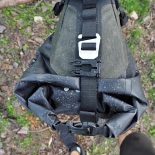 Popruh upínající drybag v postroji Scape Seat Bag s aretační sponou a masivním hliníkovým háčkem.