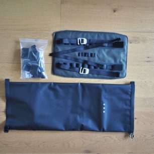 Vybalený Brooks Scape Handlebar Roll. Vidíme drybag, postroj a v pytlíku sadu podložek a aretačních spon.