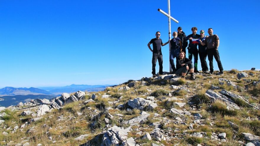 červená boudička, betonový patník a nedaleko stojící vrcholový kříž na špičce Sinjalu, pohoří Dinara, Chorvatsko