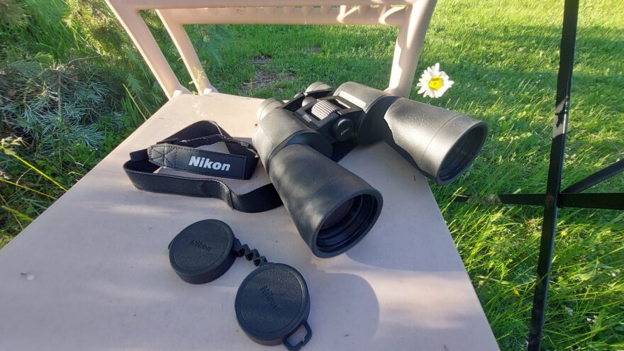 Dalekohled NIKON ACTION ZOOM je opatřen popruhem a ochranou skel