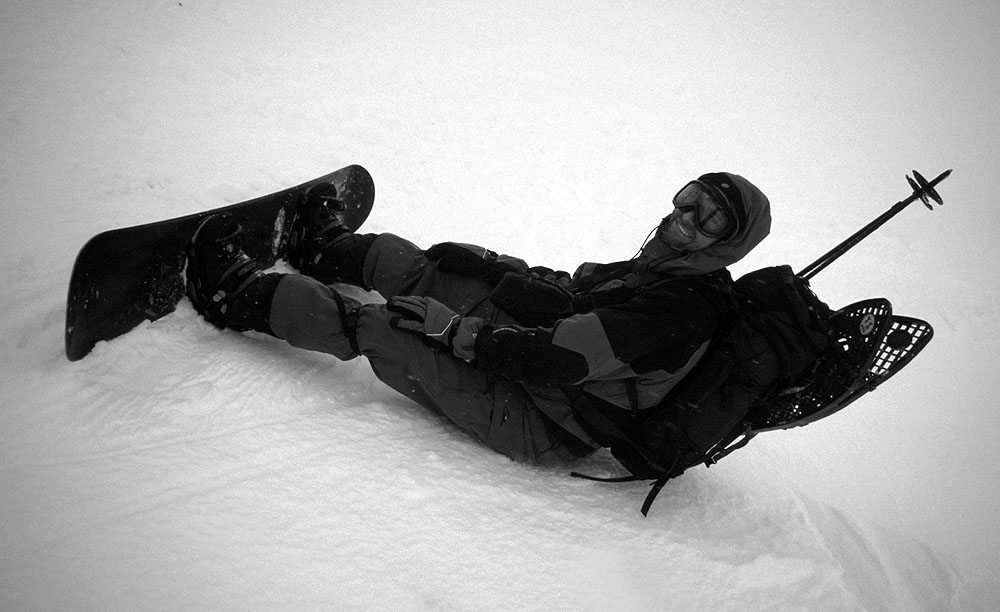 S plnou polní včetně sněžnic na batohu při sjezdu na snowboardu