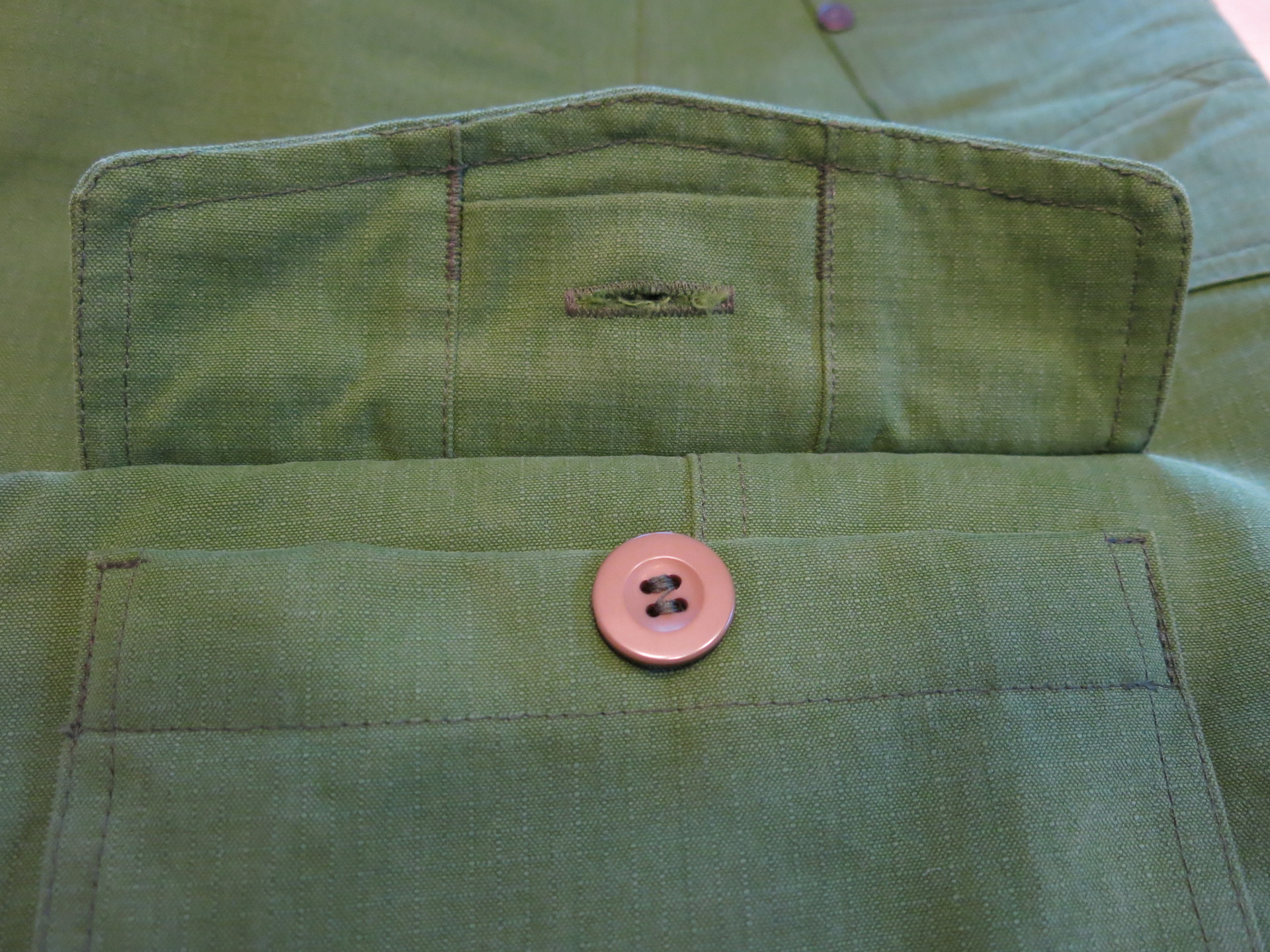 Detail kryté knoflíkové dírky na kapse