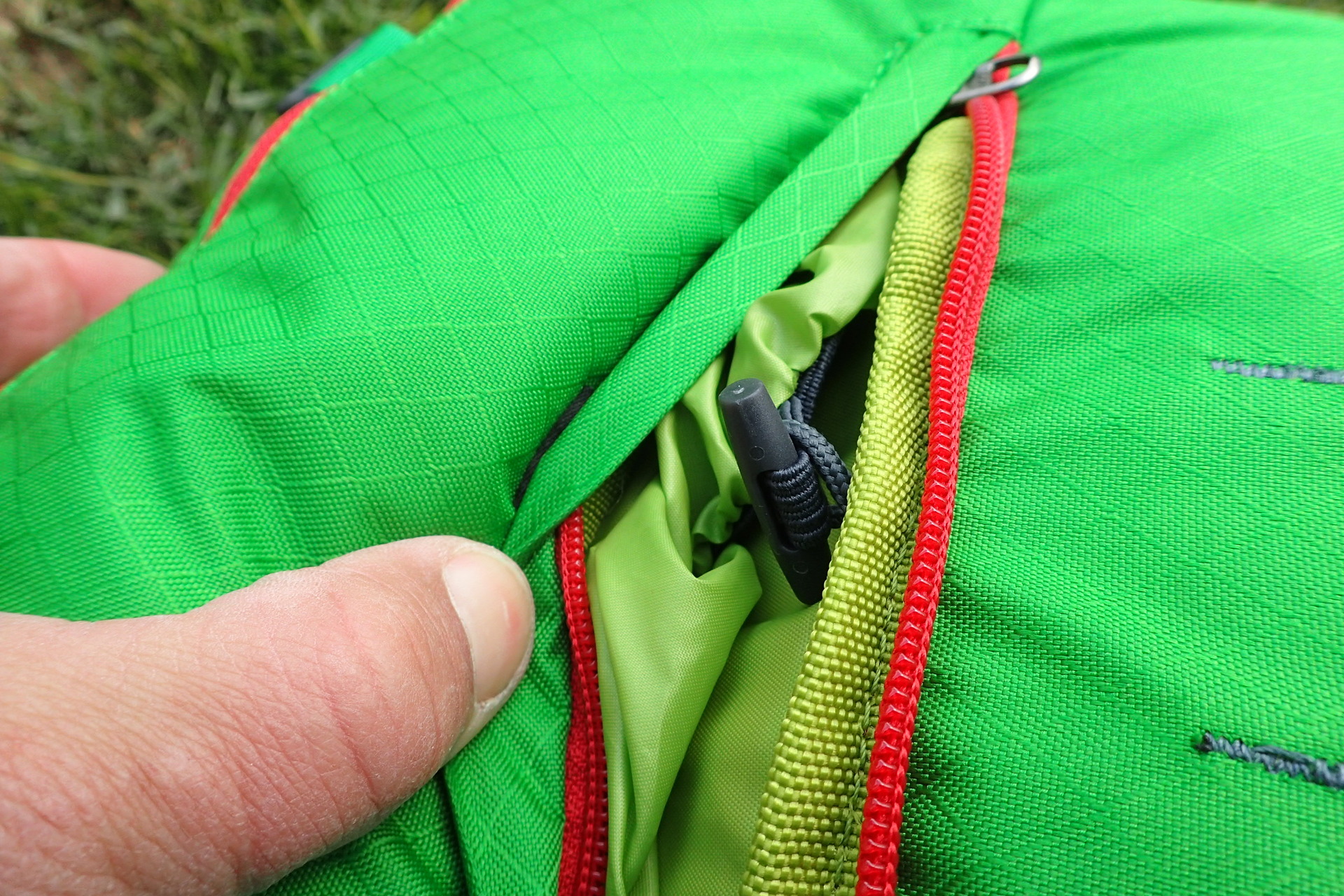 Pod tímto zipem ve víku batohu se skrývá velká pláštěnka, která se dá vyjmout.