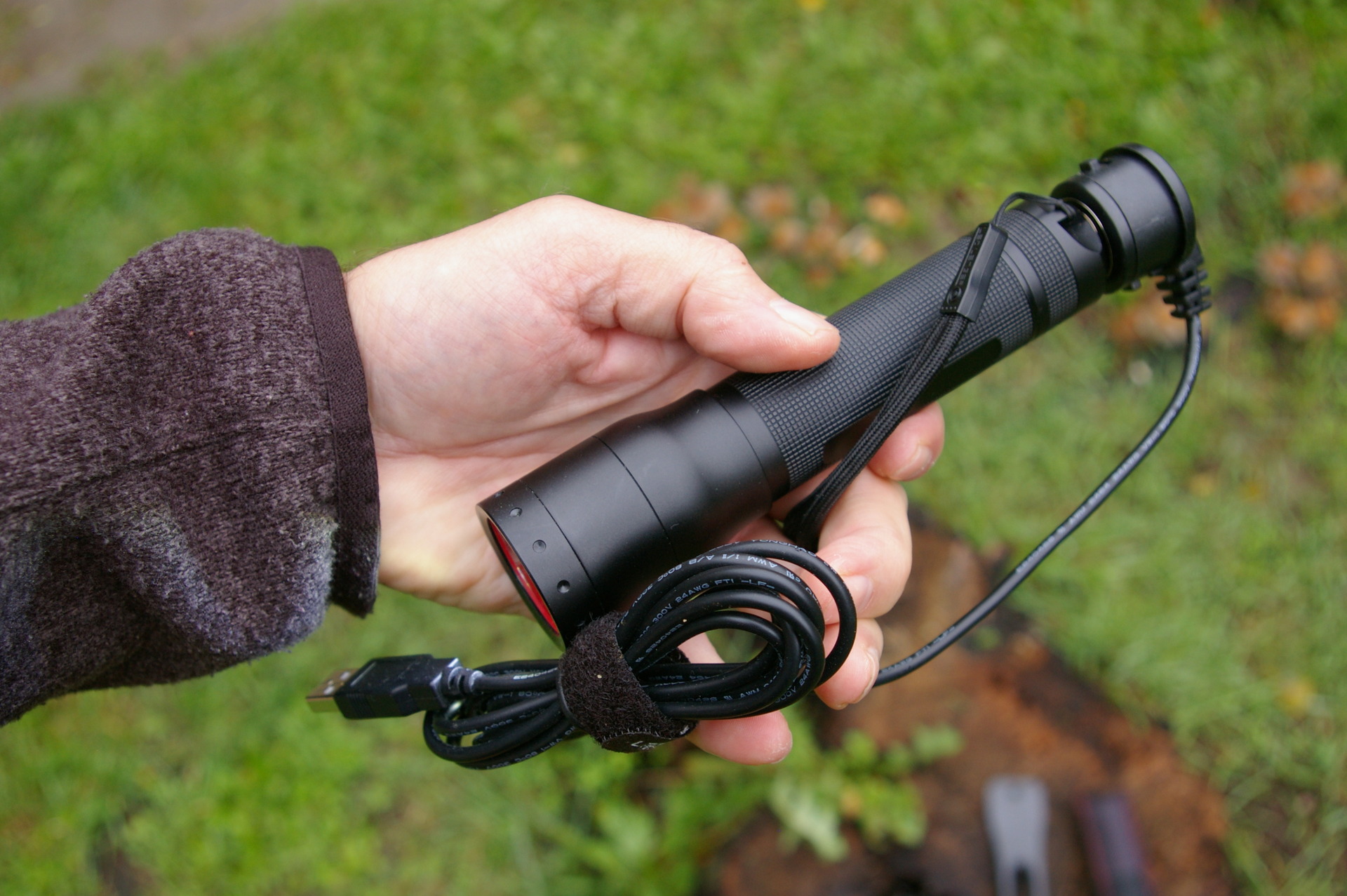 Svítilna Led Lenser P7R s připojeným nabíjecím kabelem.