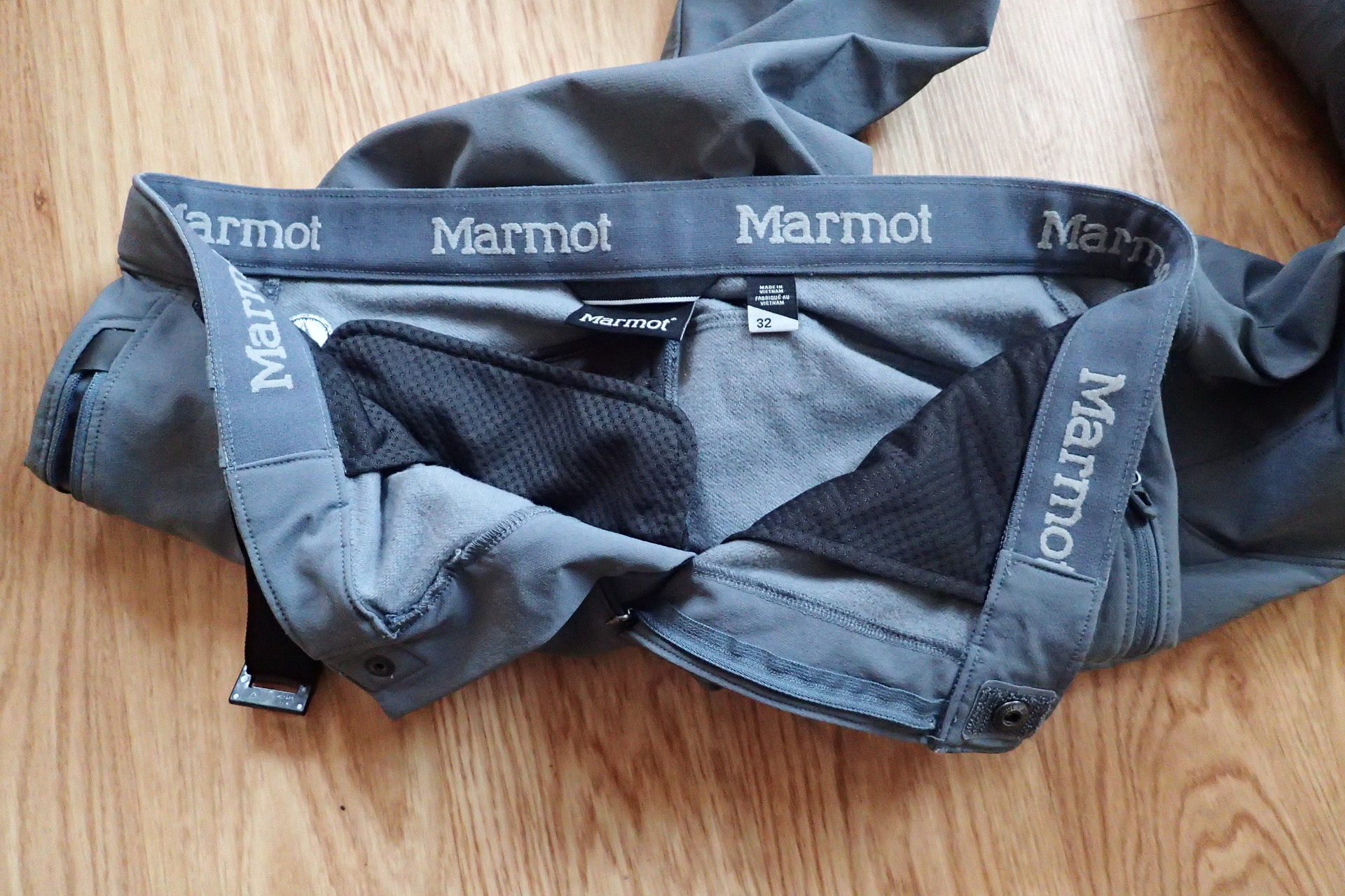 Vnitřní strana kalhot Marmot TOUR PANTs poutkem, označením velikosti a zapínáním.