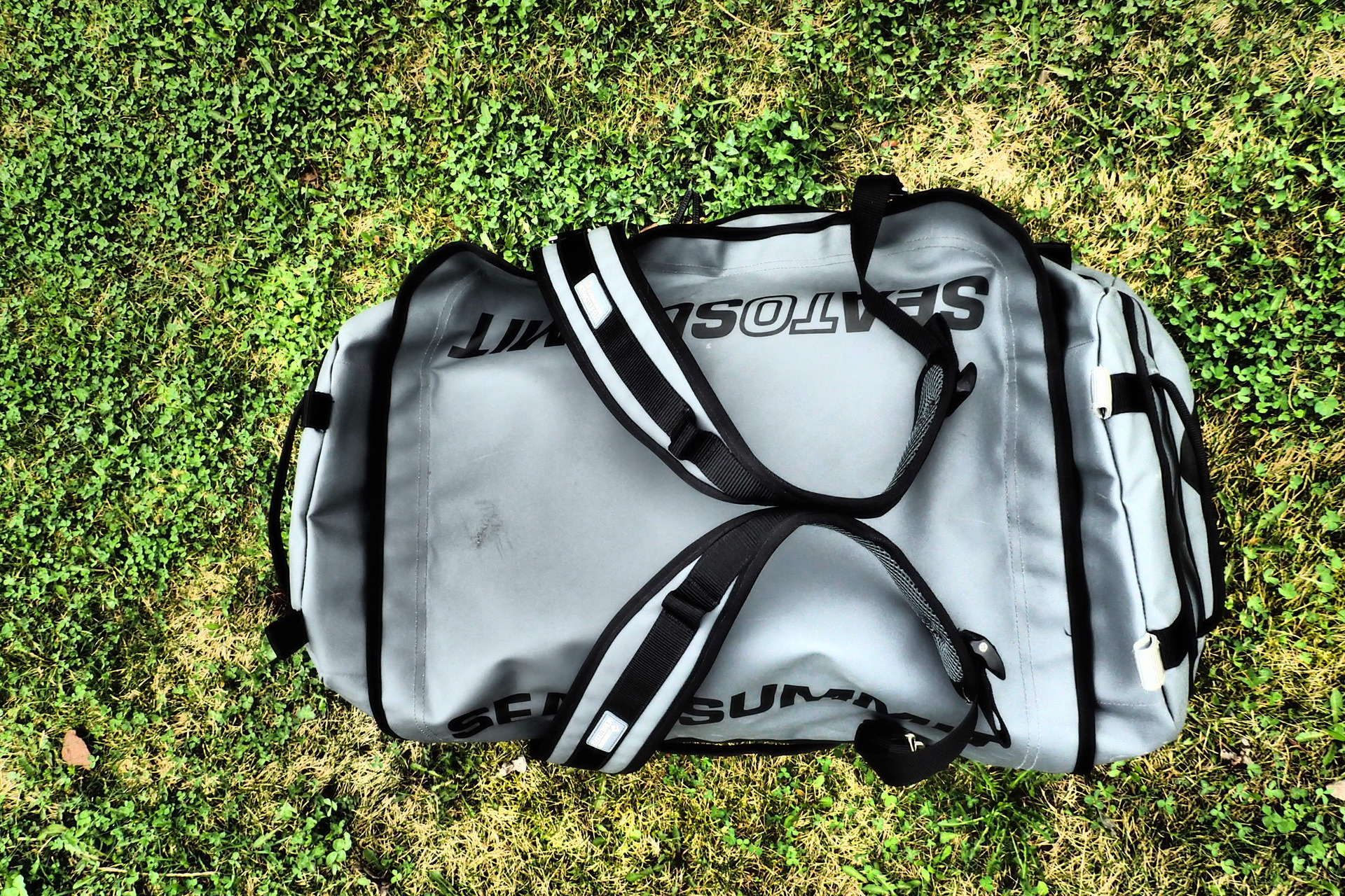 Díky magnetům drží popruhy tašky Sea to Summit Duffle bag 90 u sebe.