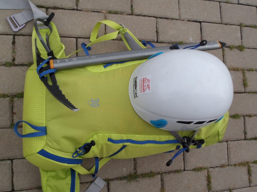 Fixace helmy na batoh Salomon X ALP 30 pomocí pružných tkanic se samosvorku určených pro cepín nebo teleskopické hole.