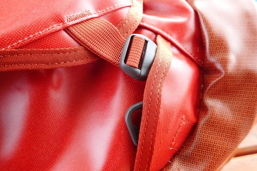 Detail na sponu víka a fixace ramenního popruhu na tašce OSPREY Transporter 65.