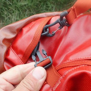 Zajištění víka tašky a otočná spona ramenního popruhu na tašce OSPREY Transporter.