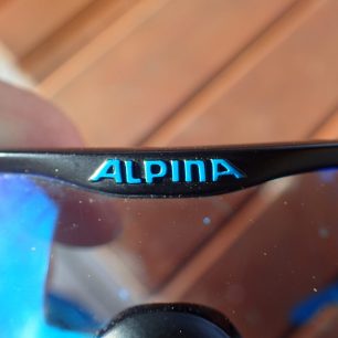 Logo ALPINA nad nosníkem v barvě nožiček brýlí Alpina S-Way.