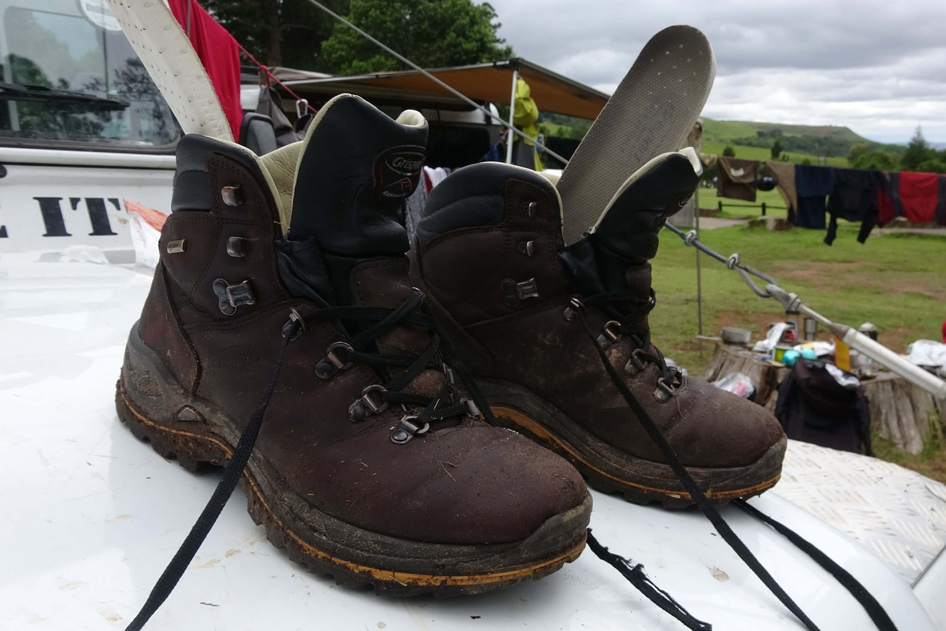 Detailní pohled na kompletně promočené boty, do nichž ale voda natekla horem po mokrých nohavicích a z vysoké trávy.