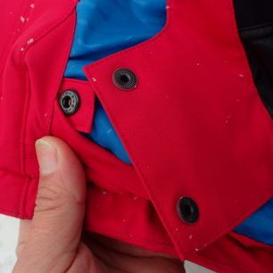 Volné konce sněhového límce bundy HANNAH Goetz lze zajistit pomocí druku.