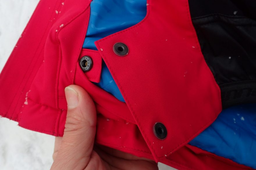 Volné konce sněhového límce bundy HANNAH Goetz lze zajistit pomocí druku.