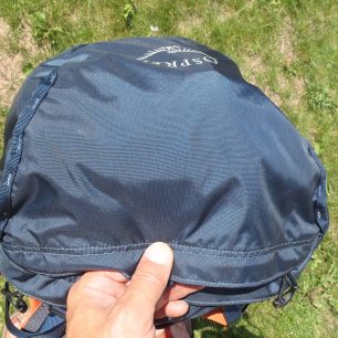 Popruhové žebříčky na víku batohu Osprey Mutant 38 slouží i pro fixaci síťky na helmu.