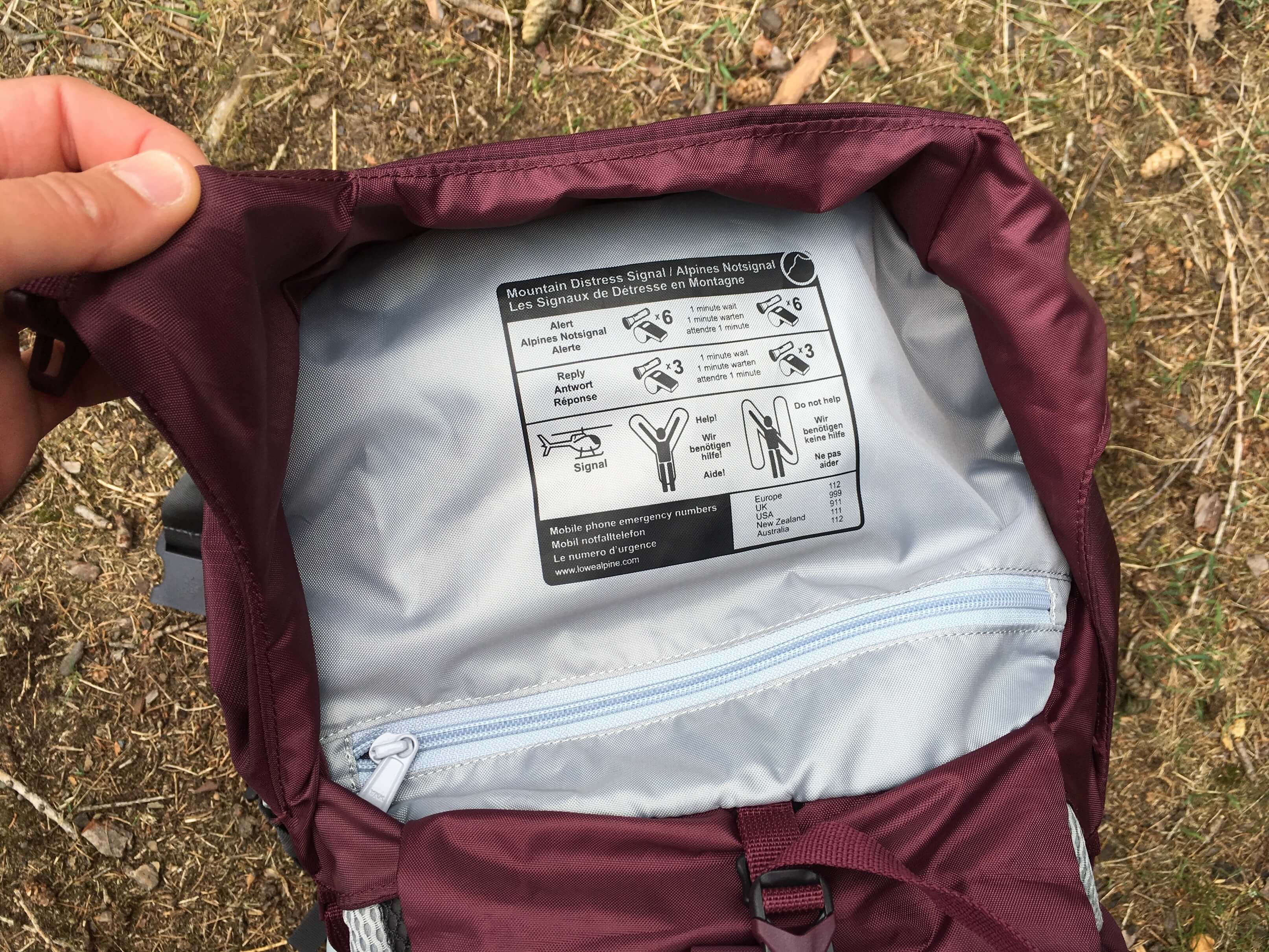 Vyobrazení nouzových signálů a kapsička na zip na spodku víka.