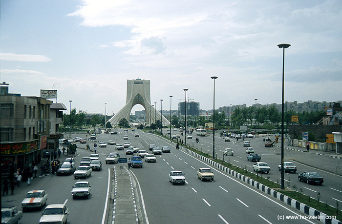 Pohled směrem na západ přes monument Azadi, v popředí typická dopravní situace v Teheránu. Na silnici jsou sice nakreslené pruhy