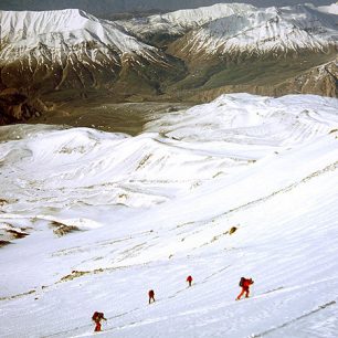 Čtveřice stoupající na lyžích ve výšce asi 4600 metrů, v pozadí mezi horami městečko Polur.