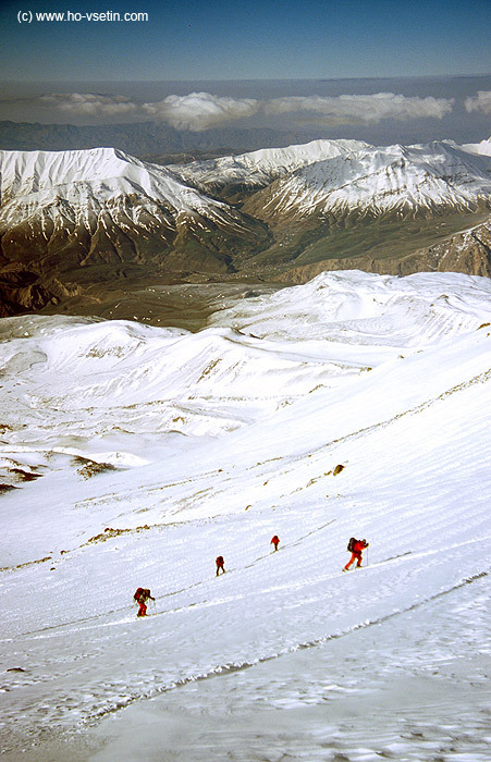 Čtveřice stoupající na lyžích ve výšce asi 4600 metrů, v pozadí mezi horami městečko Polur.