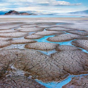 Jezero Kluane v kanadském teritoriu Yukon je nápajeno vodou z ledovců z okolních hor. Na jeho vysychajících mělčinách vzniká díky vysokému obsahu nejrůznějších minerálů rozpuštěných ve vodě barevná mozaika spletitých puklin s azurovými jezírky. Vysychajíc